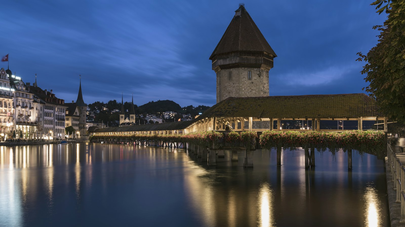 The Chapel Bridge and water tower glowing at blue hour over the Reuss in Lucerne